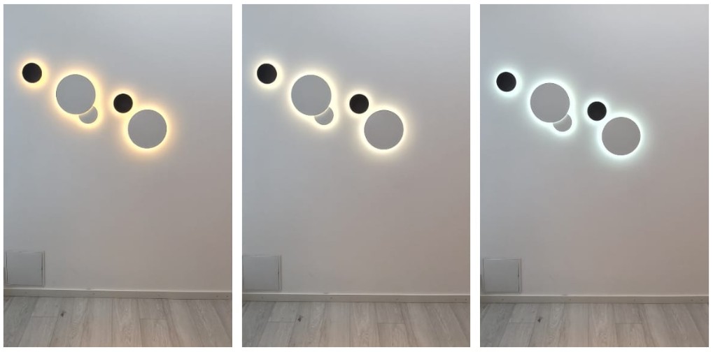 Three round wall lights in a row shine with warm, neutral, and cool shades of white against a wall – the perfect solution for creating an ambient modern atmosphere with LedStore.fi’s high-quality LED lighting solutions. - LedStore Round Eclipse wall lights grouped in a series of five fixtures. There are two sizes of the light and two of the lights overlap each others.