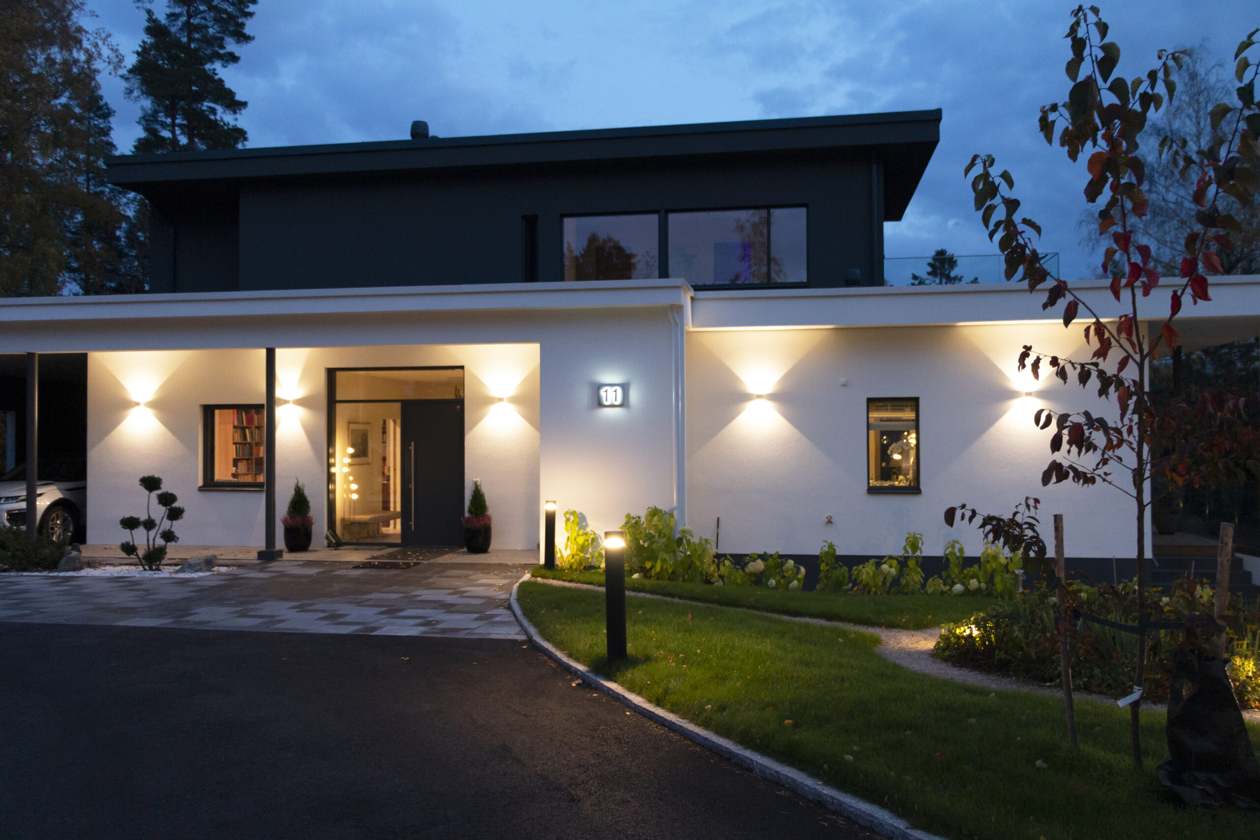 Versatile LED outdoor lighting with wall lights, bollard lights along the walkway, and spotlights near the plantings.