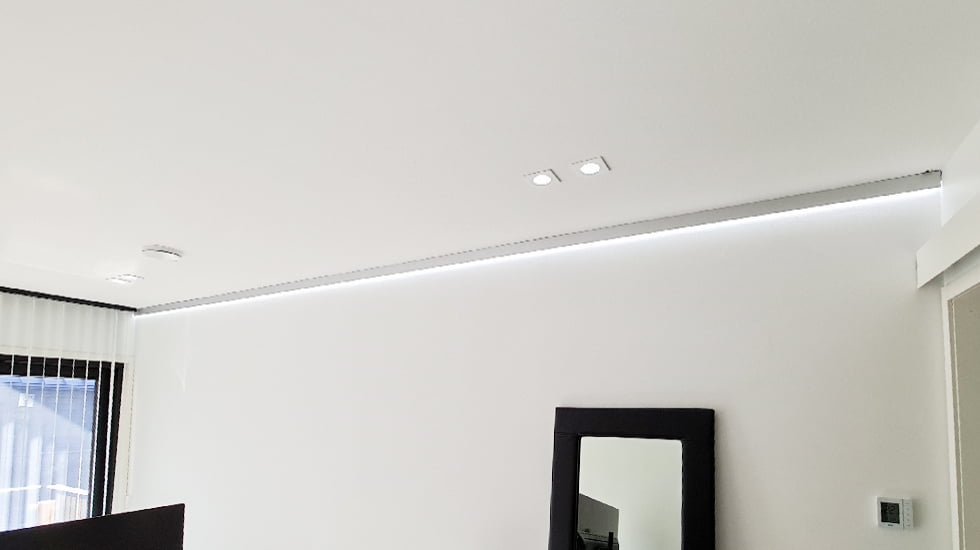 Indirect lighting placed at the ceiling and wall junction, emitting a cool white light.